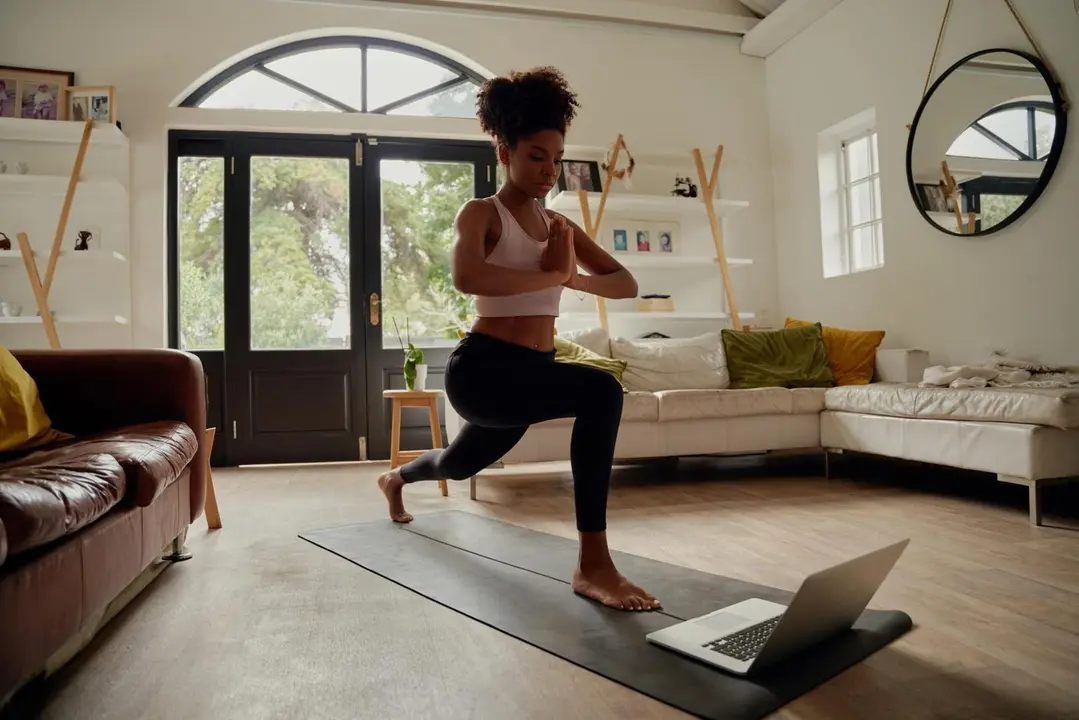 Young woman watching video on laptop while exercising