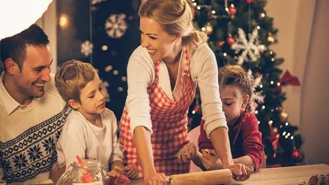 Family baking cookies for Christmas together, mother rolling dough, children helping their mother.