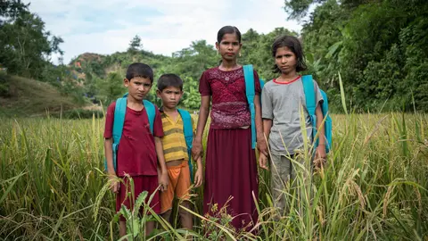 On 15 November 2017 in Bangladesh, siblings (left-right) Mohammed Anis, 8, Mohammed Safayet, 7, Sufaira, 12, and Homaira Amit Hassan, 10, pause in a field on the way to the UNICEF learning centre they attend, in the Unchiprang makeshift camp for Rohingya refugees in Cox&rsquo;s Bazar district. They are among 15,000 children receiving educational and other support at 182 UNICEF learning centres in Rohingya refugee camps and makeshift settlements in the district. In Myanmar, the siblings had been prohibited from attending school. &ldquo;In Myanmar, we do not [sic] feel happy, because the police did not allow us to go to school, or to play. They forced us away.&rdquo; Homaira says. &ldquo;We were very sad there as the police would not let us go to school,&rdquo; Sufaira said. &ldquo;We just wanted to learn and play like the other children.&rdquo; Her family, who came to Bangladesh in August, fled their homeland after their village was attacked by the Myanmar military. &ldquo;They were shooting bullets, cutting people with knives and slaughtering the people,&rdquo; Homaira said. &ldquo;That is why we fled here.&rdquo;

Since late August 2017, some 613,000 Rohingya have fled from Myanmar to neighbouring Bangladesh to escape the violence in their homeland. More than half of them are children &ndash; many in dire need of vital support. High levels of severe acute malnutrition among young children have been found in the refugee camps, and antenatal services to mothers and babies are lacking. Expanding the provision of safe water, sanitation and improved hygiene for Rohingya children is the top priority, and support for children traumatized by violence needs to be expanded. UNICEF focus also includes providing Rohingya children with learning and support services in child-friendly spaces. In camps and makeshift settlements in Cox&rsquo;s Bazar district, UNICEF has set up 182 learning centres that are providing 15,000 children with education, psychosocial and other support. The centres &ndash; each one operating in three shifts,