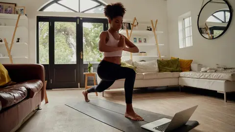 Young woman watching video on laptop while exercising