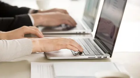 Close up image of female and male employers hands typing together on laptop keyboards at desk. Financial experts monitoring economical indicator online. E-commerce business team daily computer routine