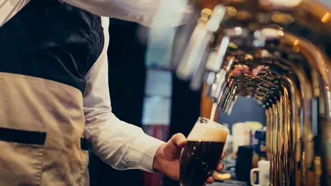 Handsome bartender pouring beer in pub